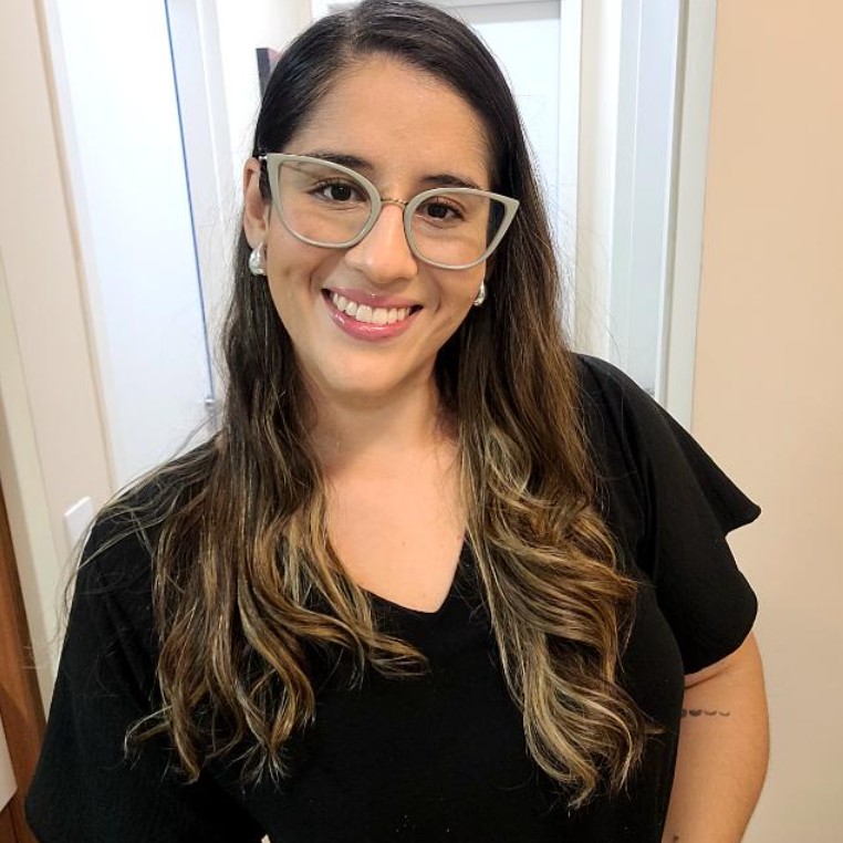 Psicóloga Izabelli Ferreira sorrindo em seu consultório