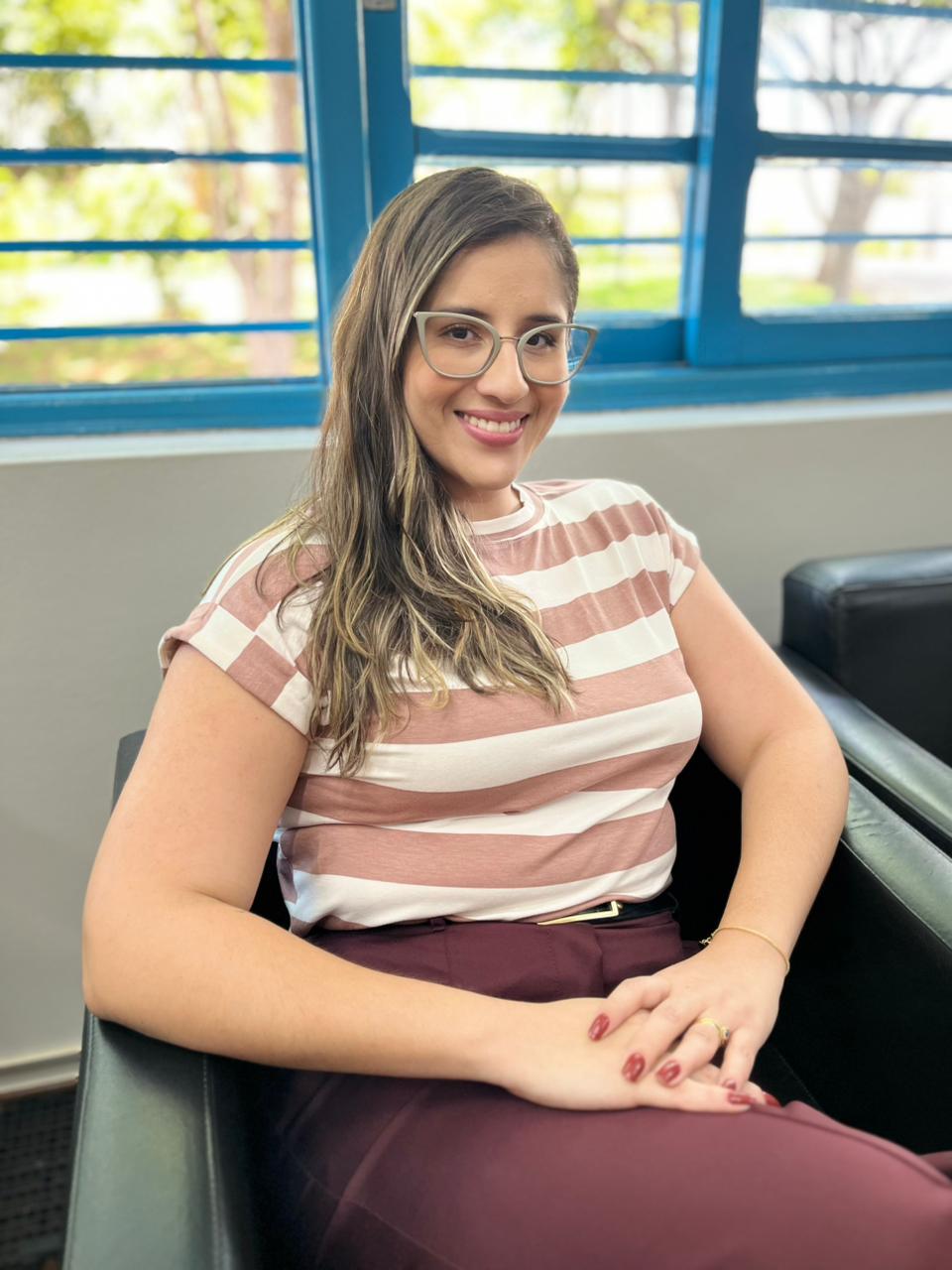 Psicóloga Izabelli Ferreira sorrindo em seu consultório